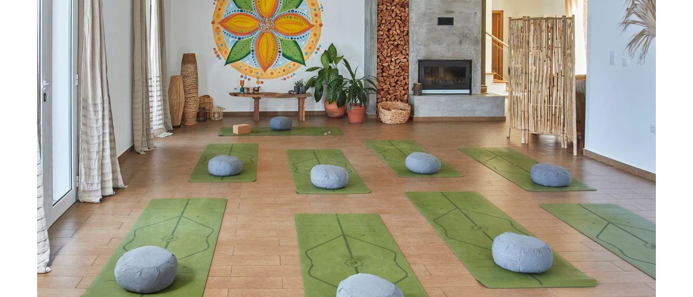 Studio with green yoga mats and blue round cushions laid out for a group session