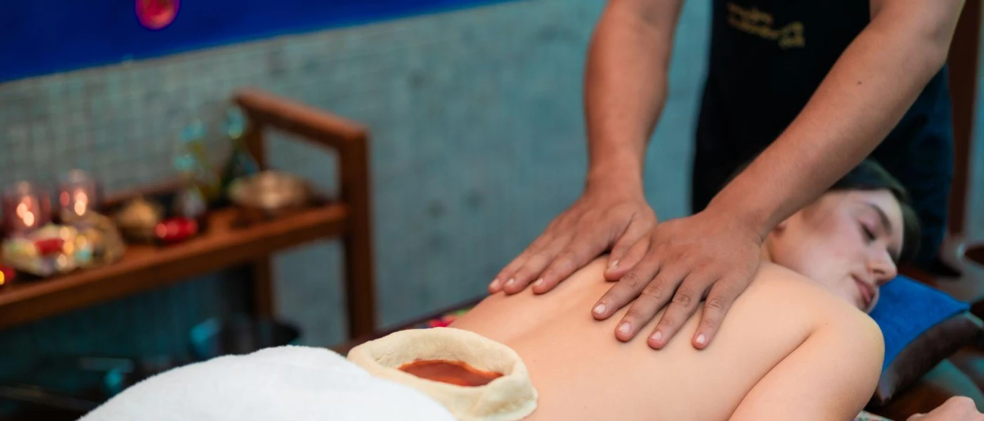 Woman lying on a massage bed while a therapist rubs her back