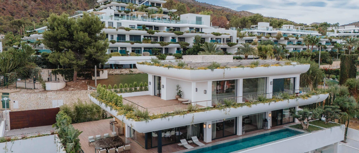 Layered white resort on a leafy hillside, with a swimming pool, lawns and terraces in a tiered design