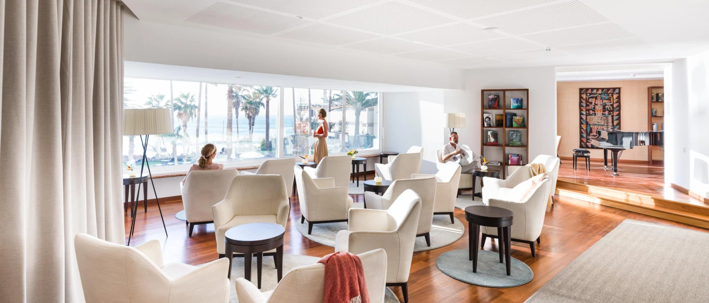 Light-filled room with large windows, book shelves and tables and chairs