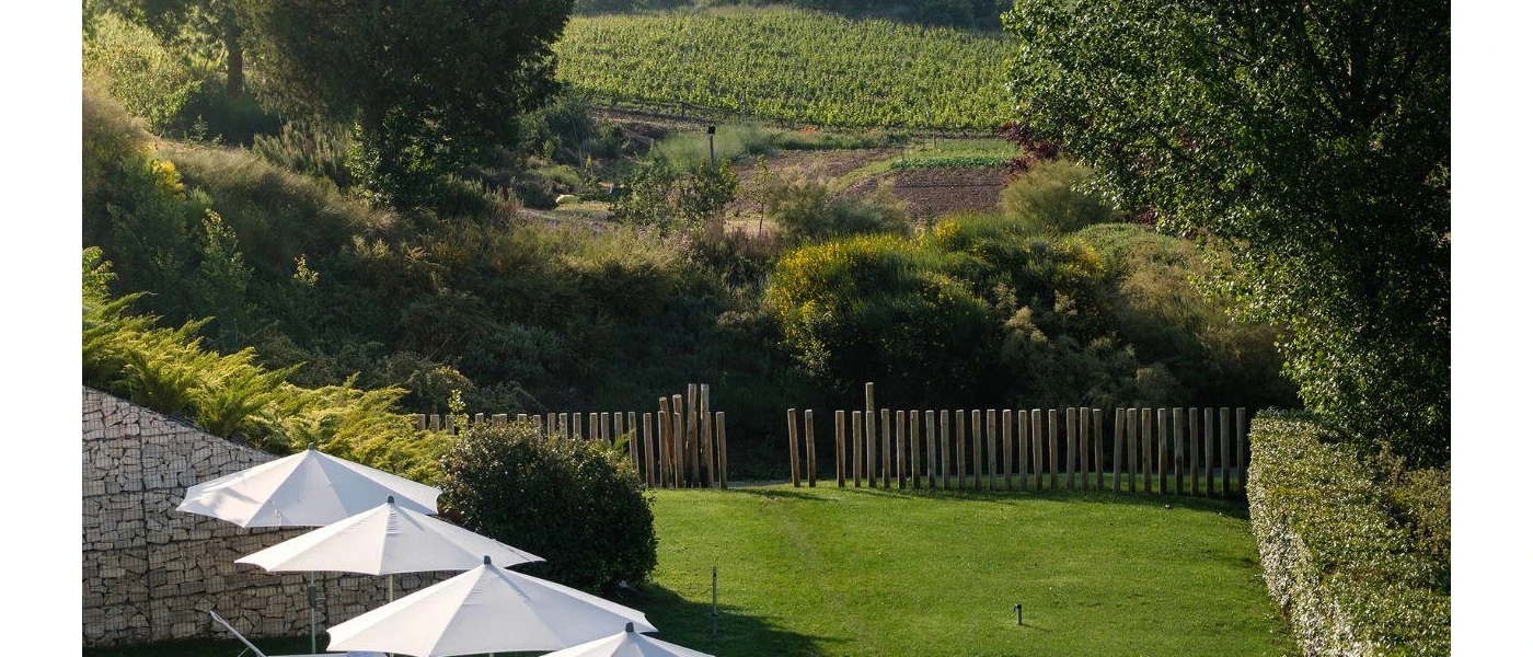 Grassy lawn in front of a row of white umbrellas, with a wooden gate that opens onto the Spanish countryside