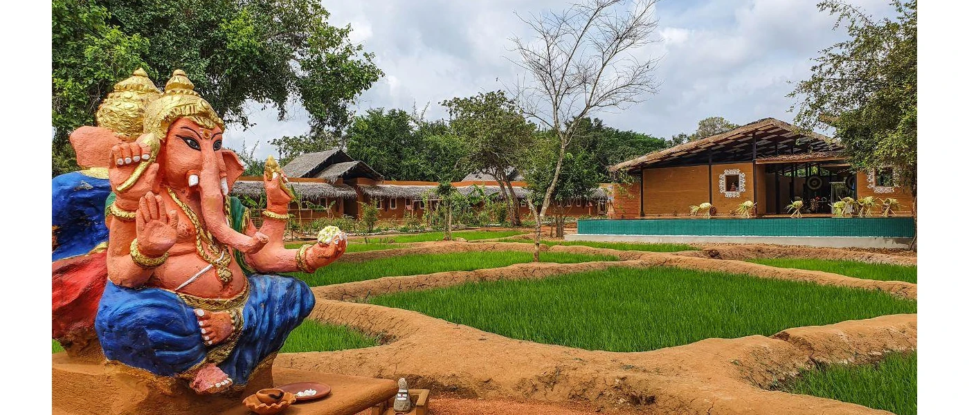 Hindu elephant statue in a leafy courtyard, with a thatched-roof pavilion in the background