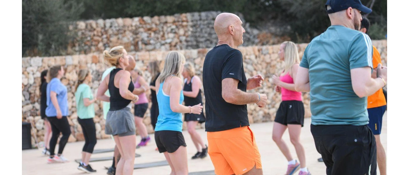Men and women in active wear take part in a fitness class in a stone outdoor courtyard