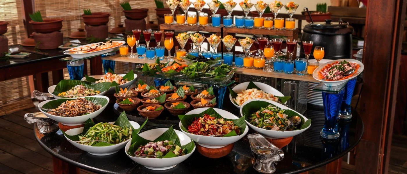 Buffet table set up, with glasses of blue and orange liquid, and bowls of salad and grains