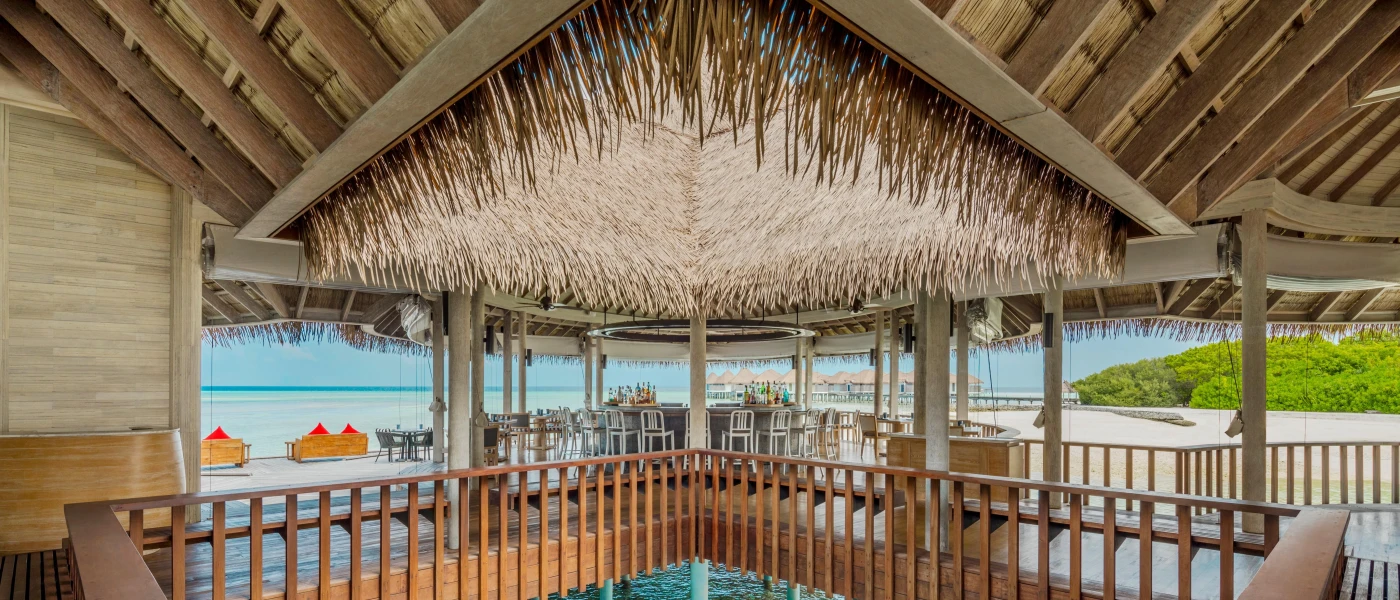 Thatched-roof open-air pavilion on stilts over water with a bar at the centre