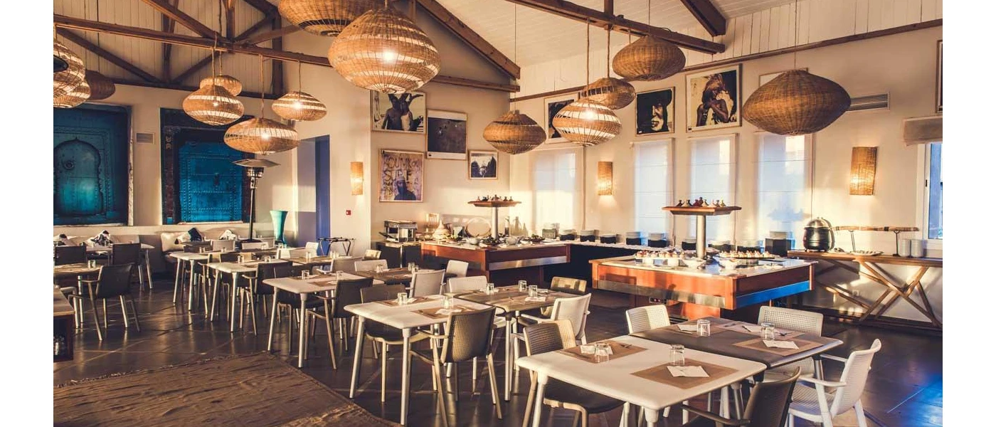 Restaurant with bohemian rattan lantern lighting, white wooden tables and dark-wood beams