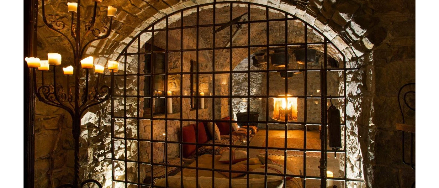 Black prison-style railings in front of a candlelit room with patterned cushions 