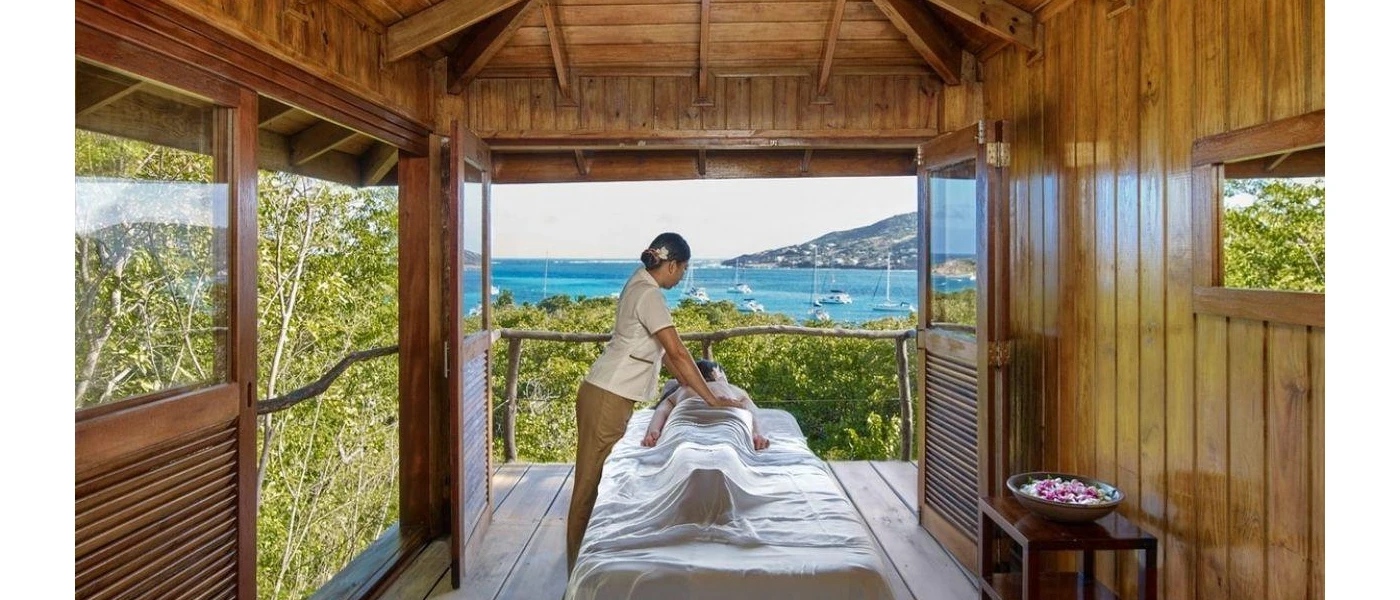 Woman in spa uniform in an open-air treatment room giving a massage