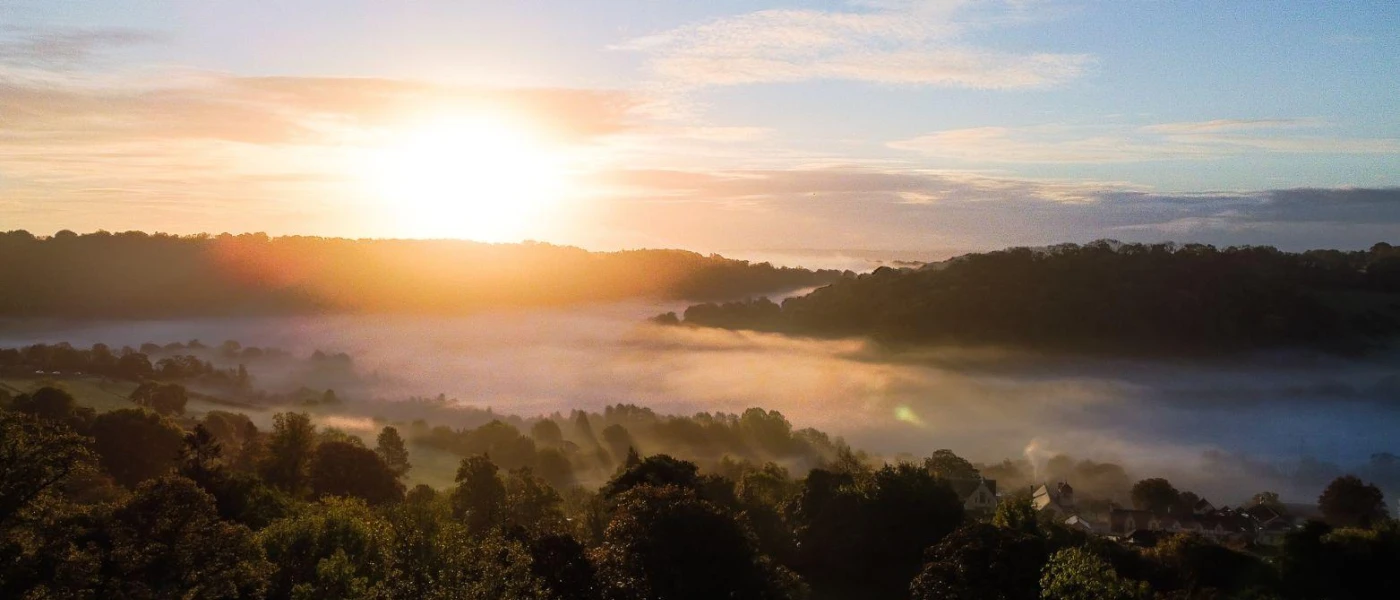 Sunset over the leafy countryside and low hanging clouds