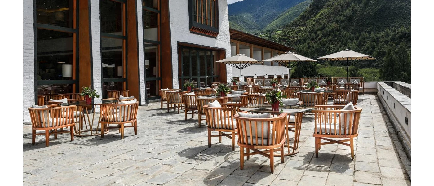 Outdoor terrace with tables and chairs and green hills in the background