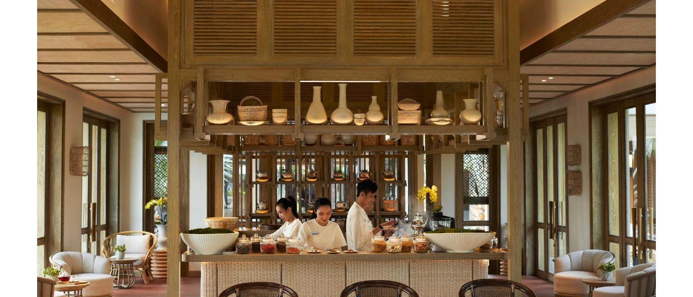 Staff members work in a central preparation area, surrounded by cream armchairs and wooden tables