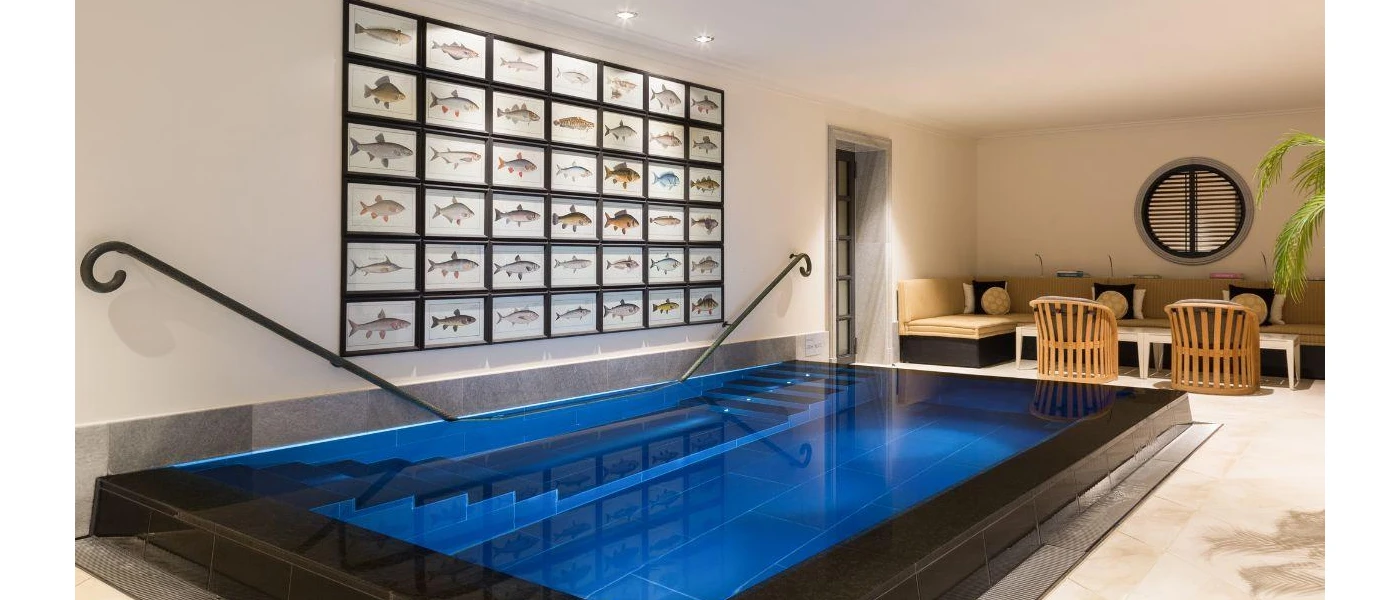 Low rectangular swimming pool next to a wooden seating area and a wall full of framed fish pictures