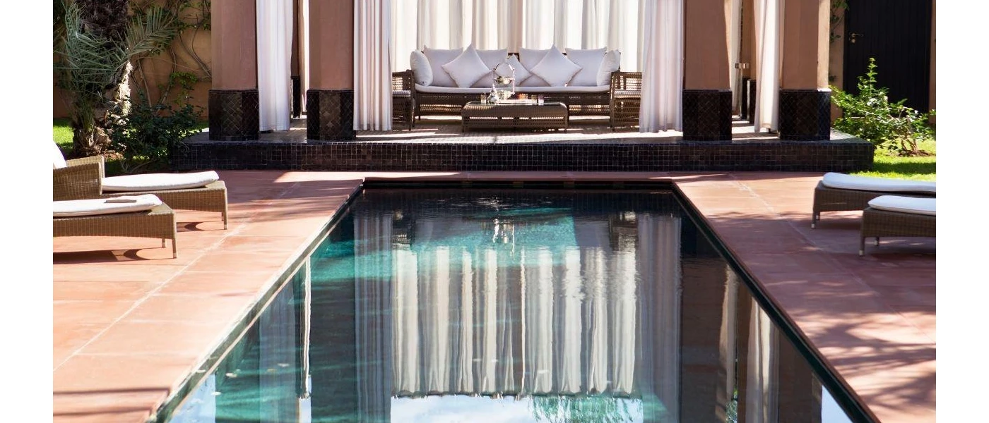 Swimming pool surrounded by white loungers and plants