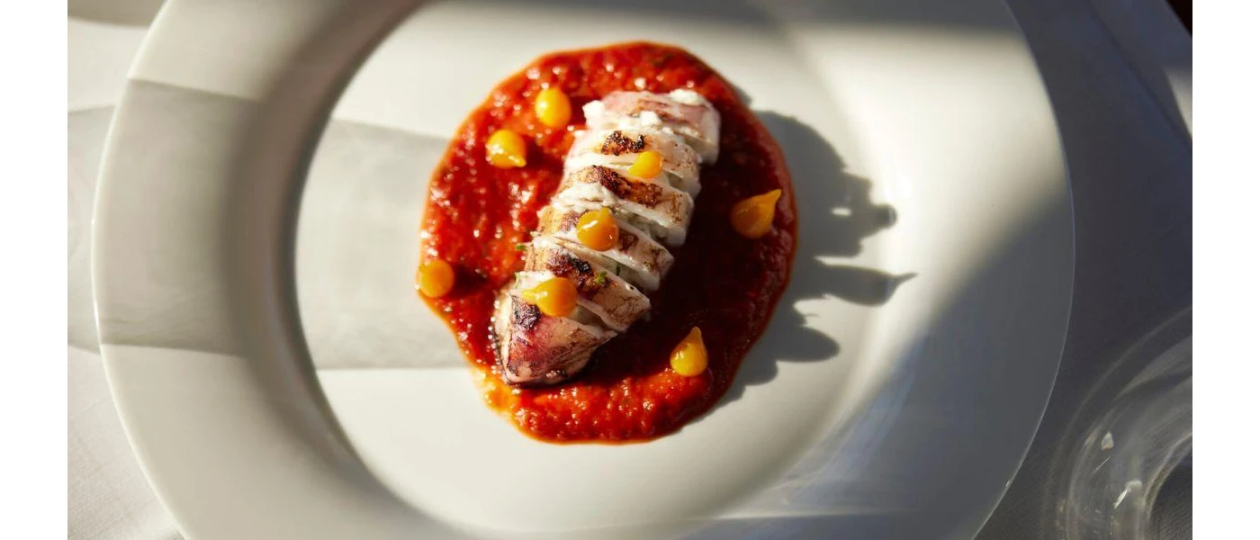 Lobster on a bed of tomato-like puree on a white plate