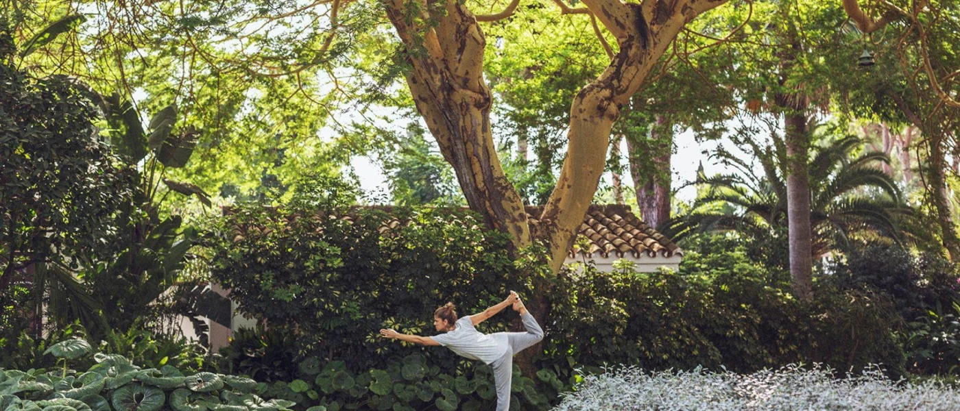Woman in grey active wear practices yoga in a tropical garden