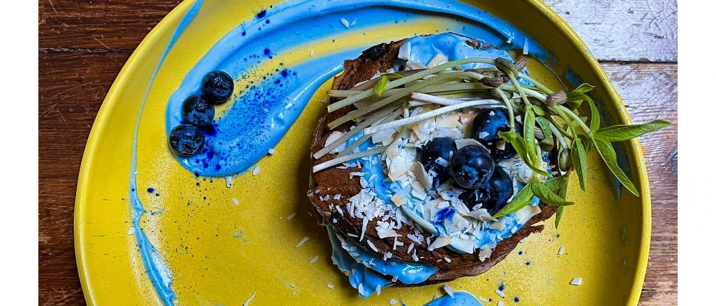 Yellow plate topped with healthy looking food including blueberries and herbs