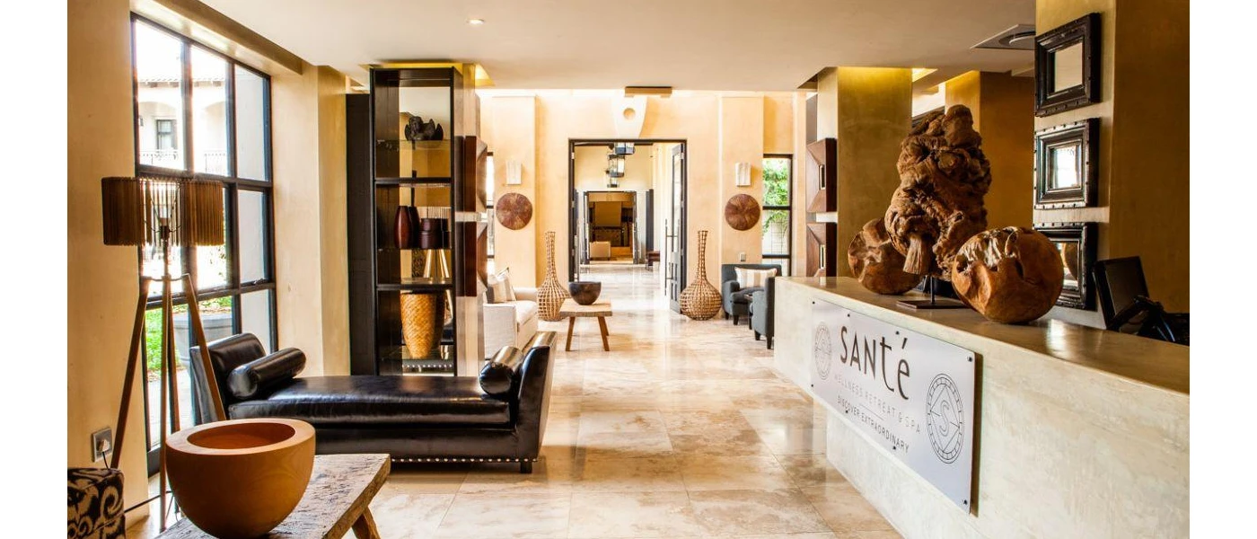 SANté Wellness Retreat & Spa entrance lobby, with a brown leather sofa, neutral floors and walls, and sculptures made from warm wood