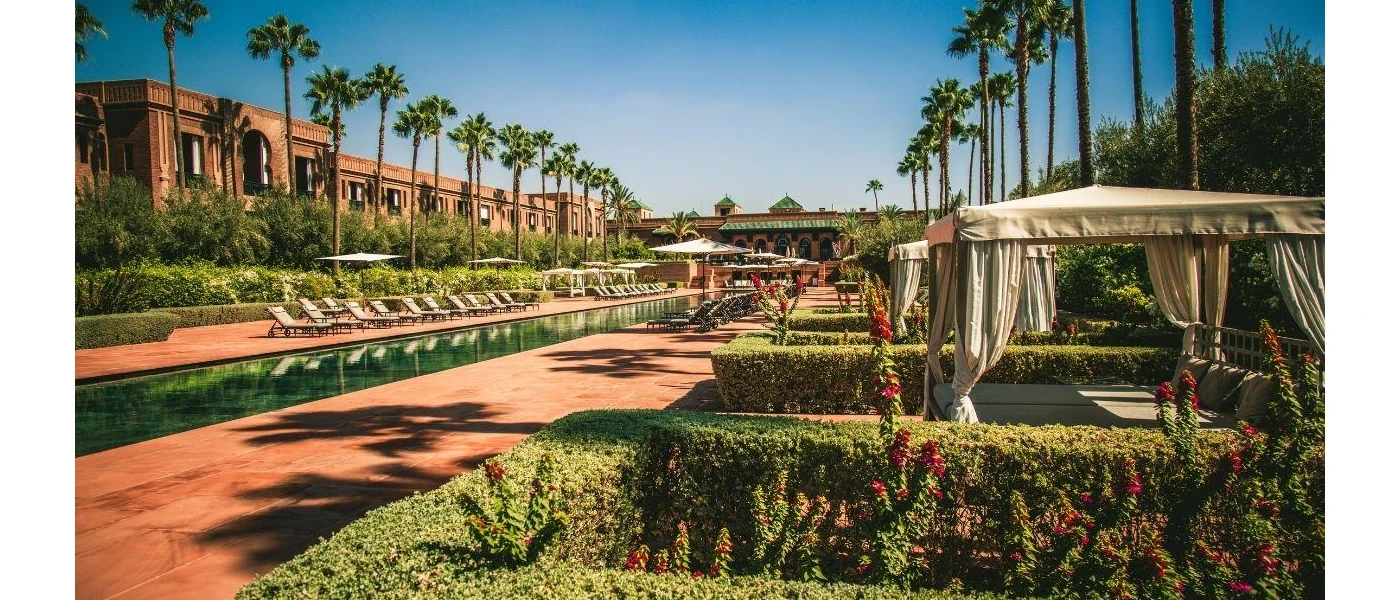 Landscapes terrace with tall palm trees, white curtained daybeds and a swimming pool