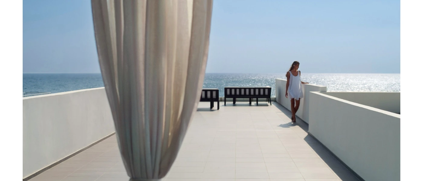 Woman in a white summer dress on a patio terrace overlooking the ocean