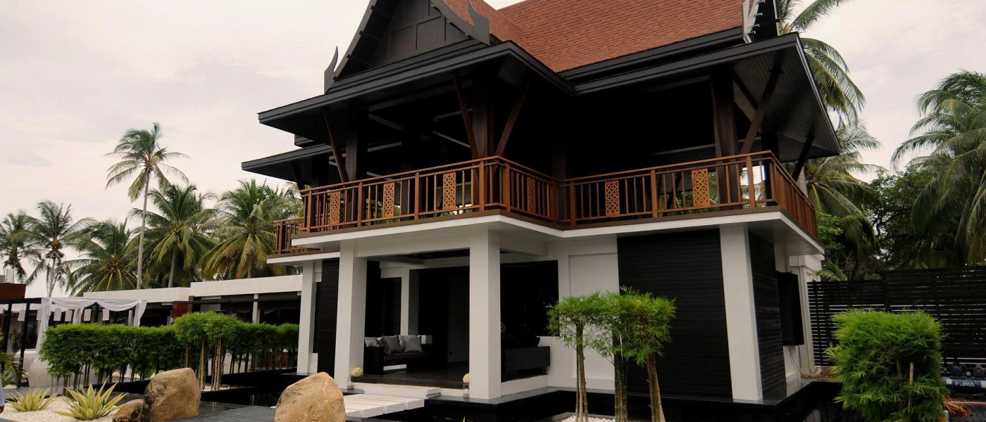 A two-storey building with a triangular roof, surrounded by palm trees