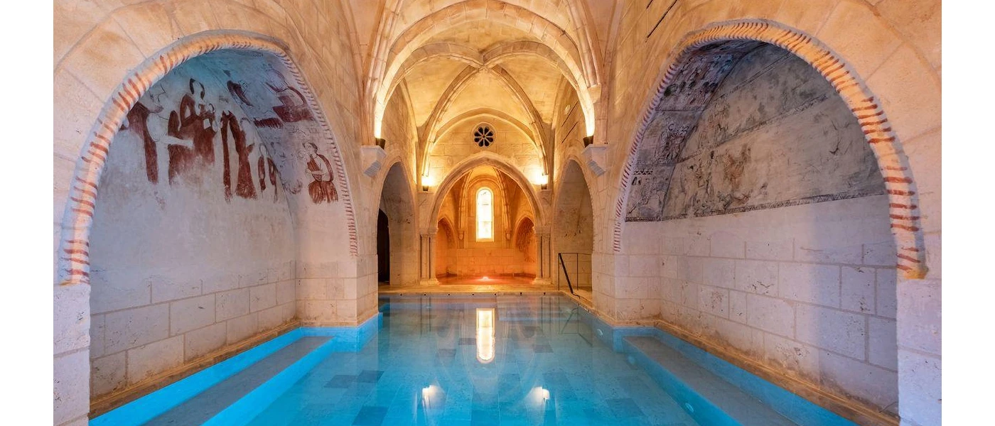 Indoor swimming pool in a room with vaulted stone ceilings and frescoes