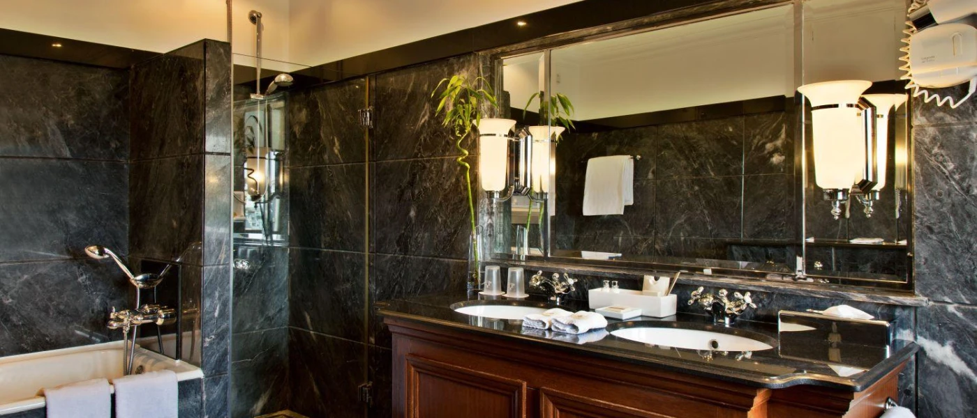 Beautiful black marble bathroom with a dark-wood vanity and two wall lights