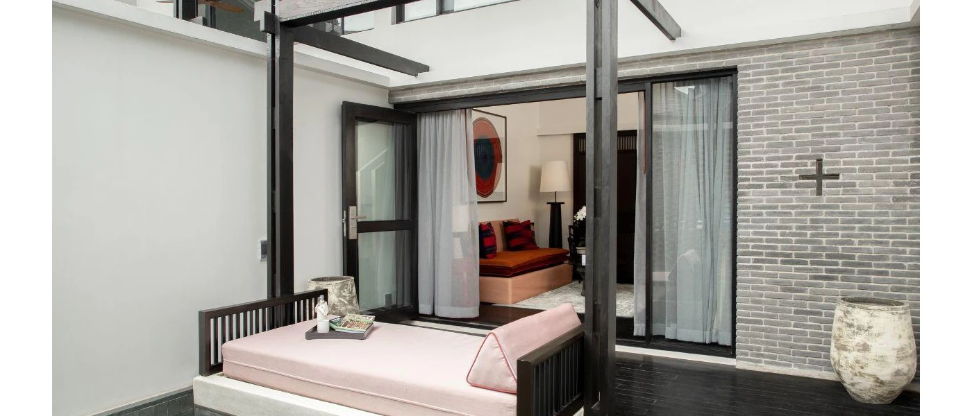 Dark-wood balcony with a daybed with cream cushions 