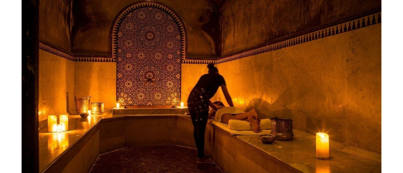 Person lying down in a hammam enjoying a massage surrounded by candlelight