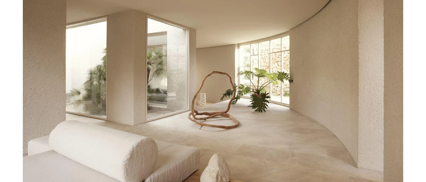 Stylish, neutral room with a plant, large windows and cushioned seating areas