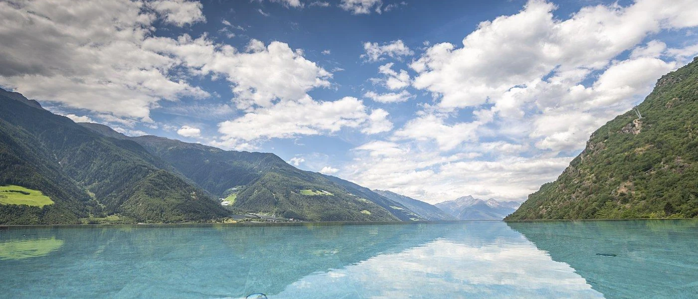 Lake reflecting the surrounding mountains and blue sky and clouds