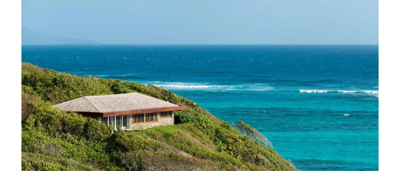 A building nestled among greenery on a hillside overlooking the ocean