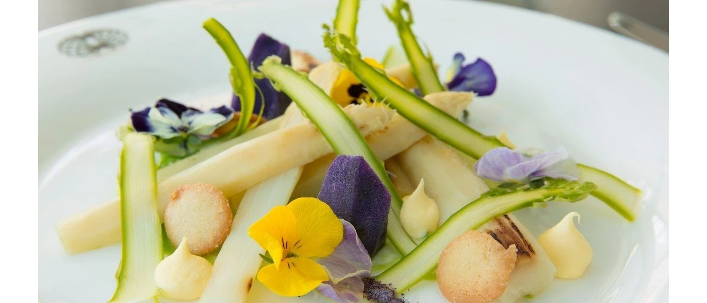 Plate of vegetables garnished with purple and yellow edible flowers