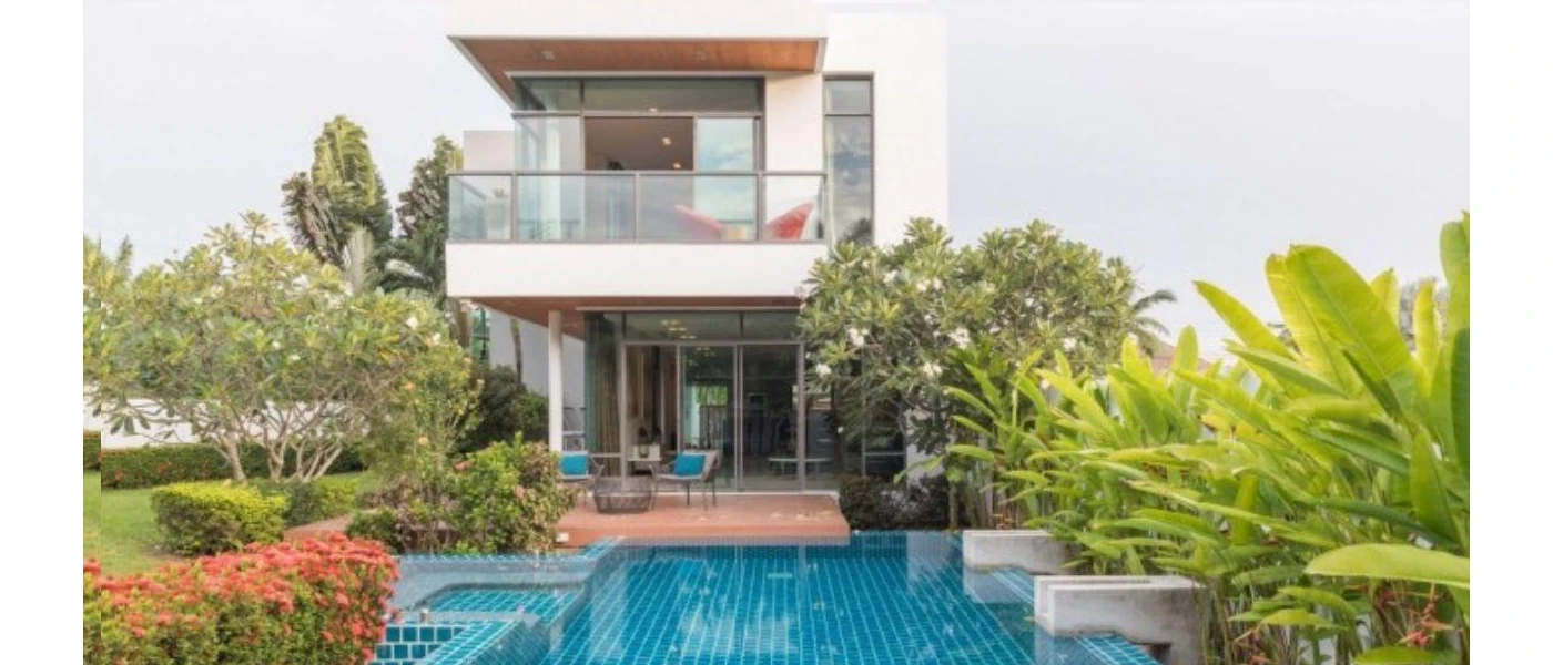 Angular two-storey villa with a glass-fronted balcony, swimming pool and gardens