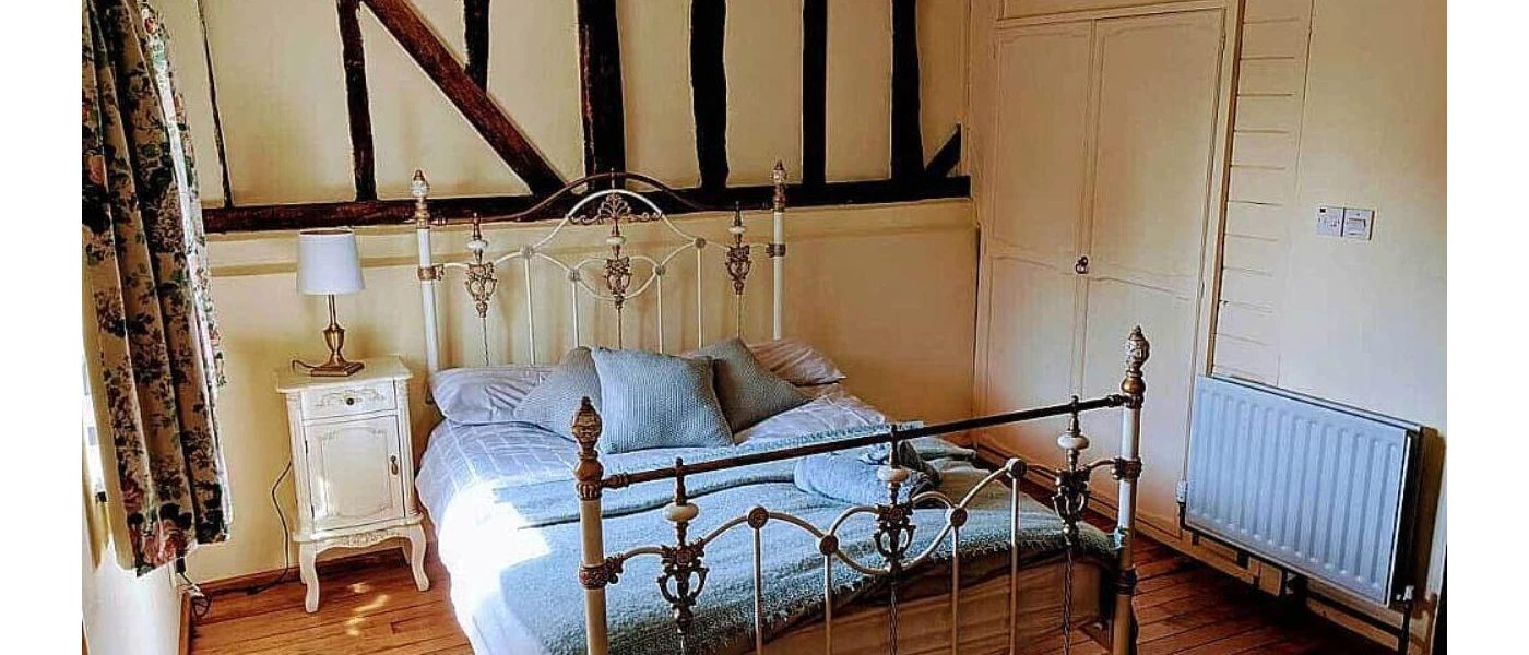 Traditional cosy bedroom with wooden beams and wrought-iron bed