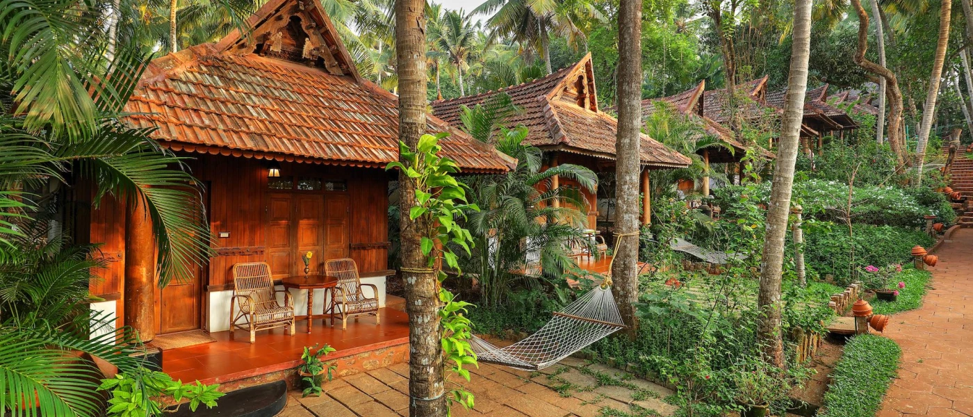 Traditional wooden huts with triangular tiled rooftops, terraces with rattan furniture and hammocks and tropical gardens all around