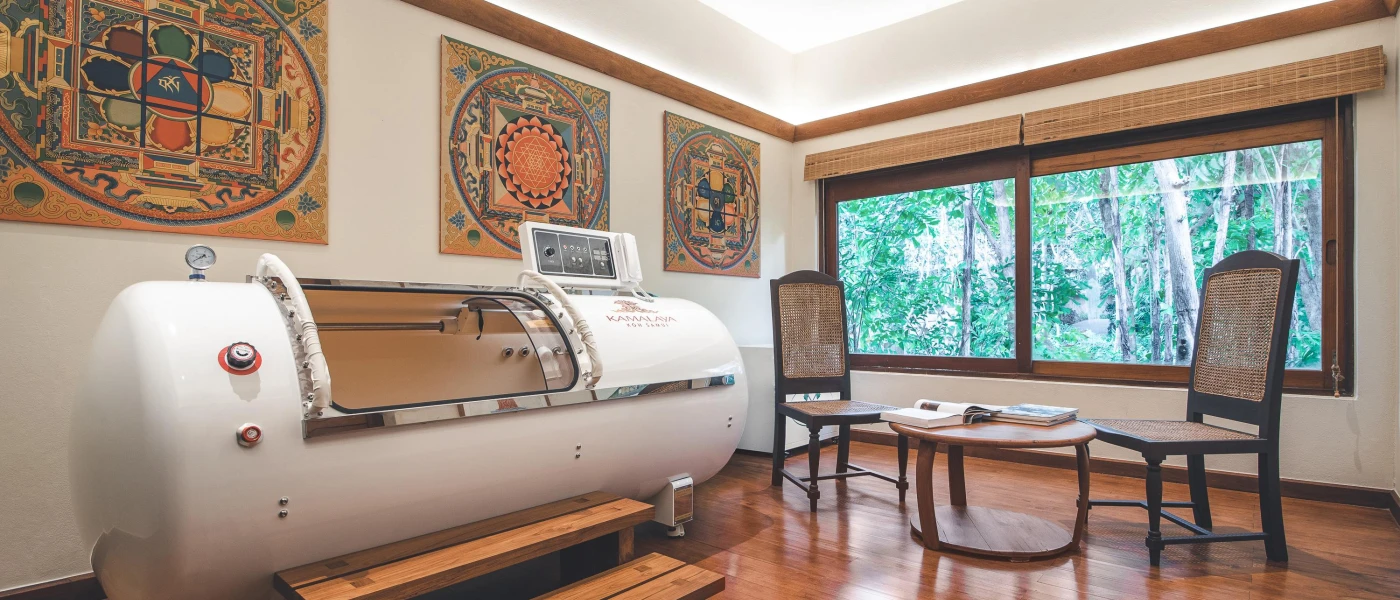 Medical chamber in an authentic room with Thai-style wall prints, a wooden table and chairs and window with a jungle view