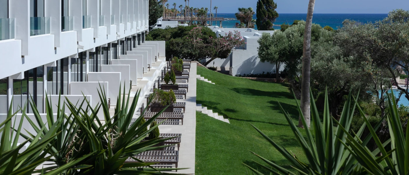 A row for furnished terraces with steps leading down to a lawned garden with the sea in the background
