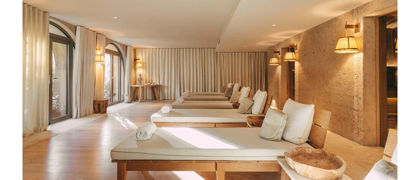 Chic relaxation room with wooden white-cushioned loungers, neutral curtains and soft lighting
