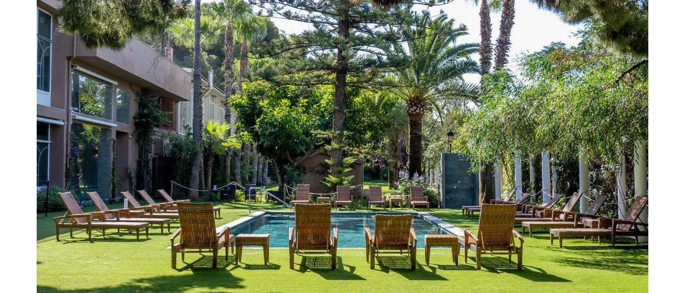 Lawn with a rectangular pool surrounded by loungers and tropical gardens