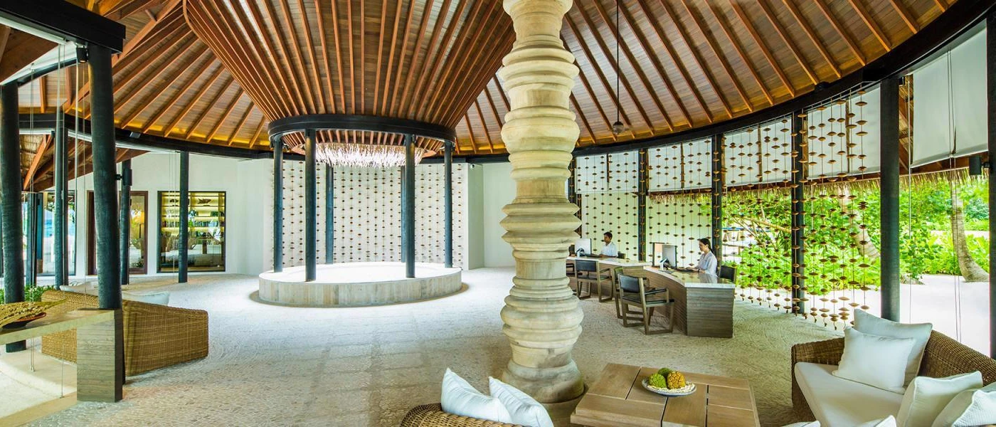 Open-sided wooden pavilion with hanging wooden decorations down the sides and staff members sitting at desks 