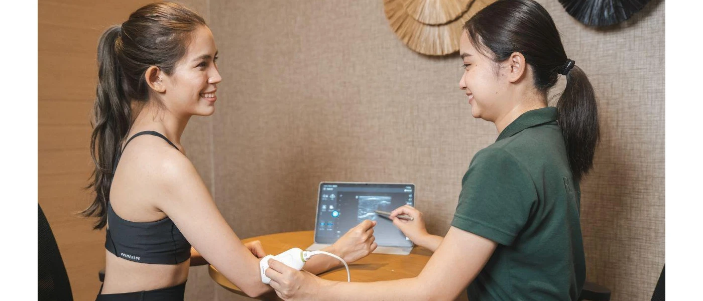Smiling woman in active wear has her arm scanned by a staff member next to a tablet
