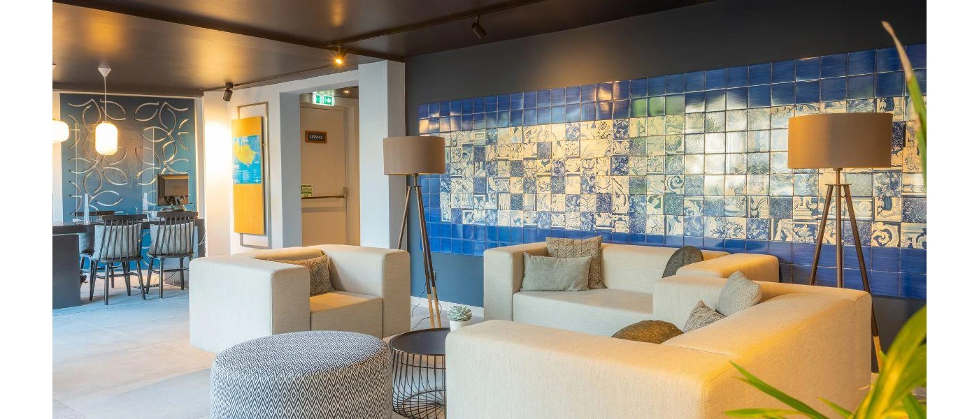Modern lobby area, with blue and white wall tiles, neutral contemporary sofas and floor lamps