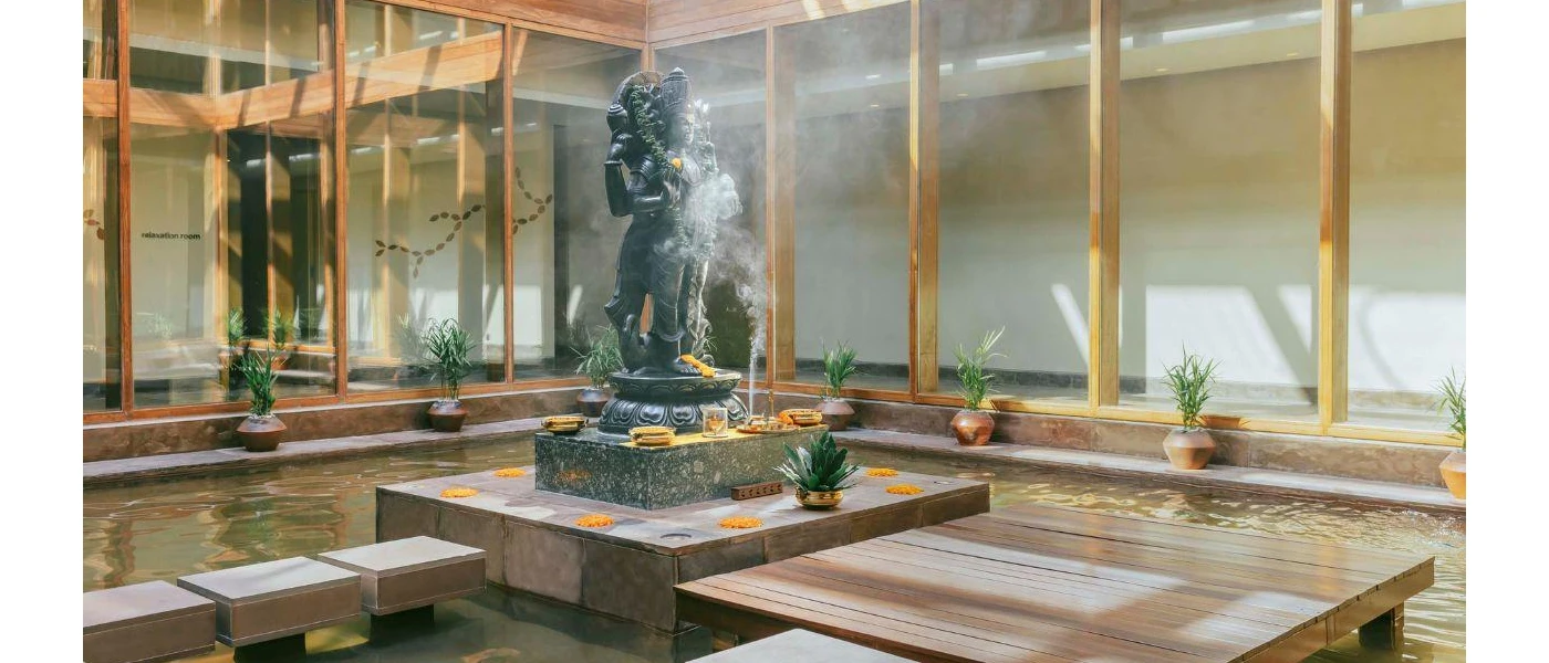 Central courtyard with a pond, Hindu statue, potted plants and clouds of incense 