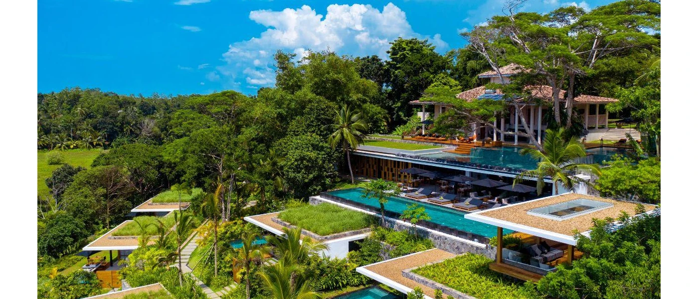 Resort staggered on a hillside shrouded in jungle greenery, with swimming pools and blue cushioned daybeds