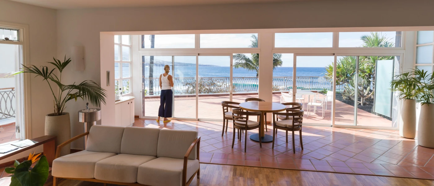 Bright room with floor-to-ceiling windows, plants and natural furniture