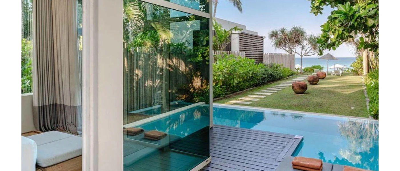 Villa terrace with a swimming pool and lawn leading down to the beach