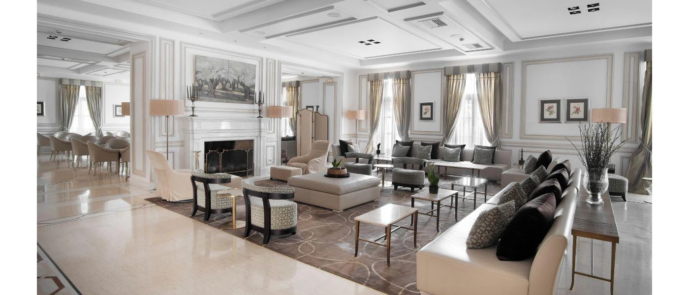 Elegant lounge area with white cushions with grey and black cushions, a swirly patterned rug and white walls