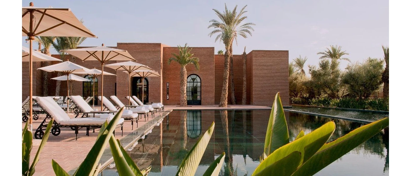 White cushioned loungers and parasols overlooking a rectangular swimming pool