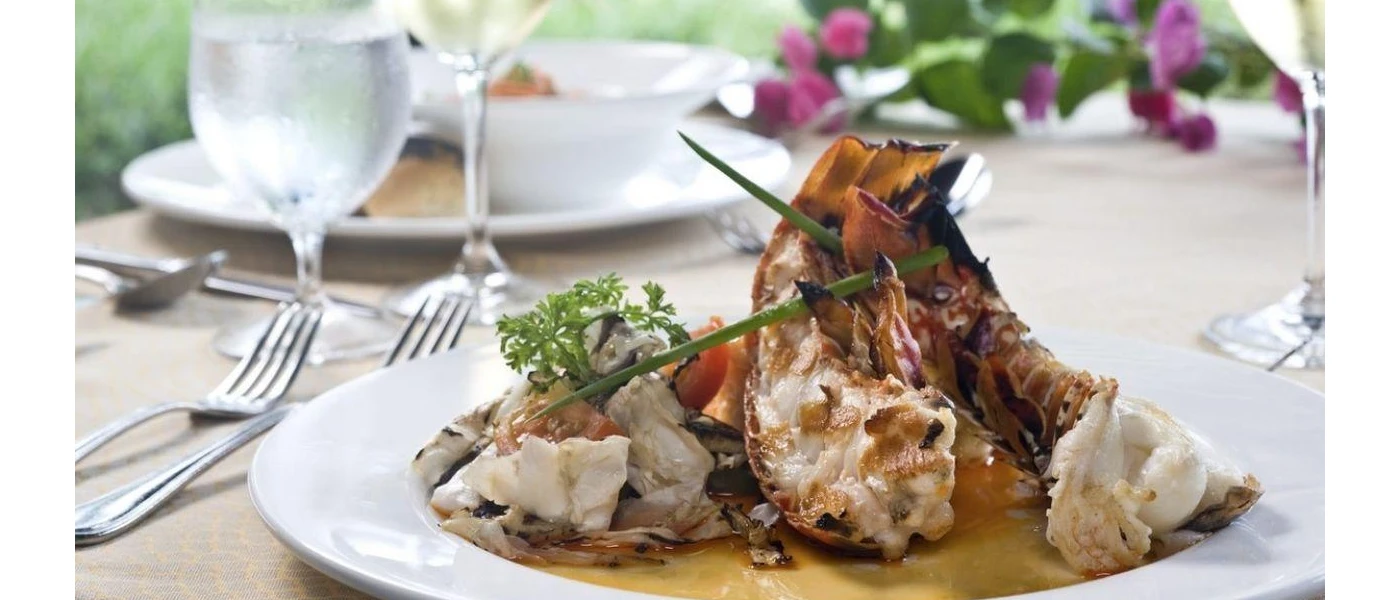 Seafood presented in a gourmet style on a white plate on a table with purple flowers in the background