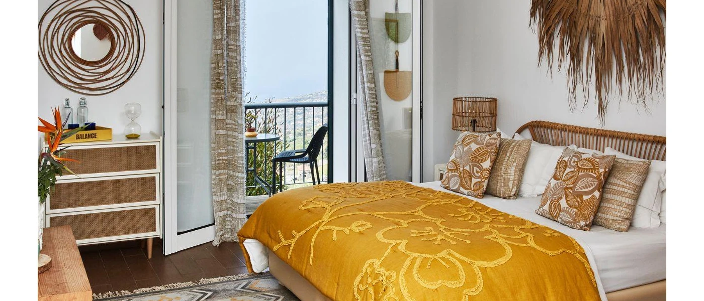 Bohemian bedroom with rattan mirror and wall hanging piece, a rattan bed with a mustard throw and patterened cushions